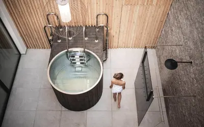 a woman walking in a bath tub in a bathroom at Biancaneve Family Hotel in Selva di Val Gardena