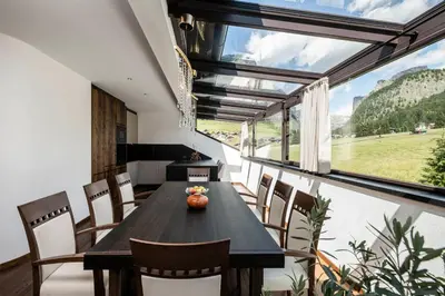 a dining room with a table and chairs and a large window at Residence Cesa Rives in Selva di Val Gardena