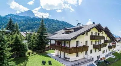 a large white house with a balcony and a mountain at Residence Cesa Rives in Selva di Val Gardena