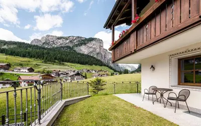 a balcony with chairs and a table with a view of mountains at Residence Cesa Rives in Selva di Val Gardena