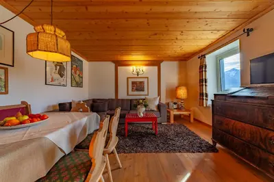 a dining room with a table and a living room at Residenza Bagni & Miramonti in Cavalese