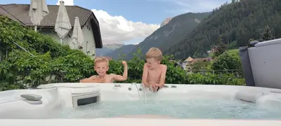 two children playing in a bath tub with water at Hotel Garni Snaltnerhof in Ortisei