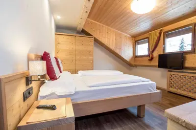 a small bedroom with a bed and a tv at Hotel Garni Snaltnerhof in Ortisei