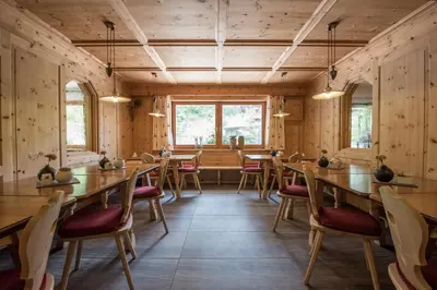 a restaurant with wooden walls and tables and chairs at Garni Hotel Bel Vert in Selva di Val Gardena
