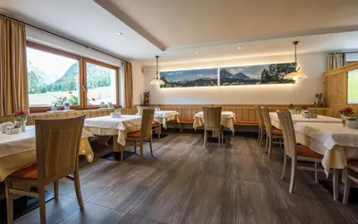 a dining room with white tables and chairs at Garni Hotel Bel Vert in Selva di Val Gardena