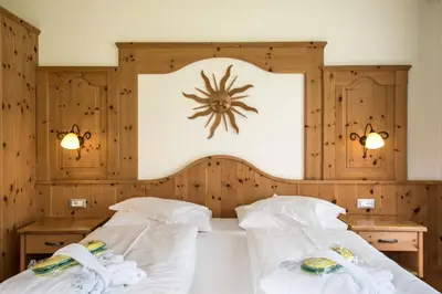 two beds in a room with wooden walls at Garni Hotel Bel Vert in Selva di Val Gardena
