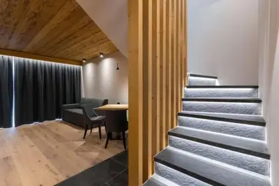 a staircase in a room with a table and chairs at Arnica Mountain Hotel in Soraga