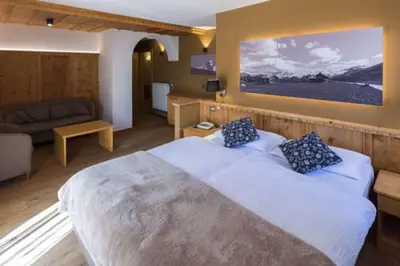 a bedroom with a large bed and a couch at Arnica Mountain Hotel in Soraga