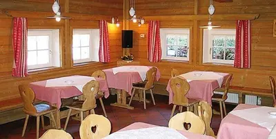 a restaurant with pink tables and chairs and windows at Arnica Mountain Hotel in Soraga