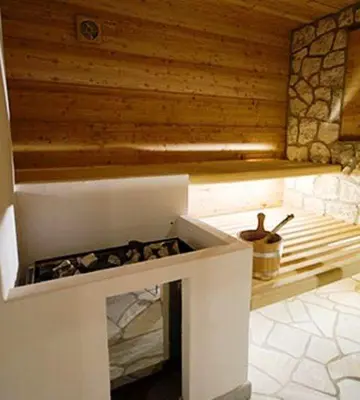 a kitchen with a white stove with a wooden wall at Arnica Mountain Hotel in Soraga