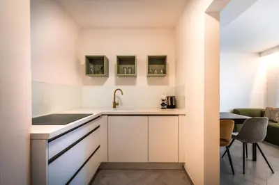 a kitchen with white cabinets and a sink at goldfinger + suites in Lana
