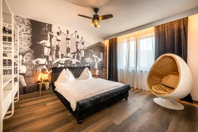 a bedroom with a large bed and a chair at goldfinger + suites in Lana