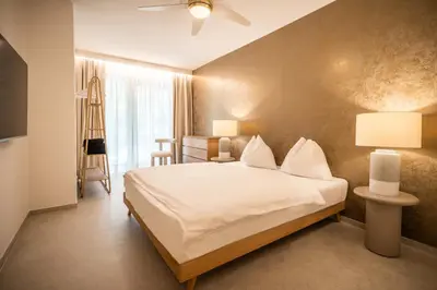 a bedroom with a large bed with white sheets at goldfinger + suites in Lana