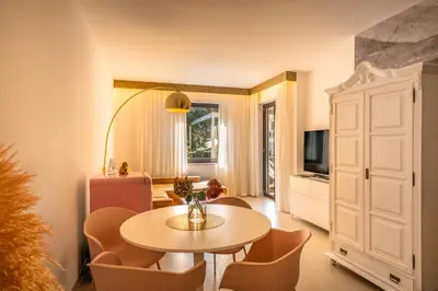 a living room with a table and chairs and a television at goldfinger + suites in Lana