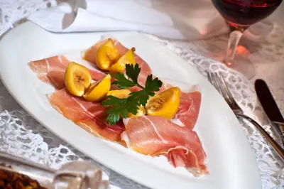 a plate of food with meat and fruit on a table at Geniesserhotel Messnerwirt Olang in Valdaora