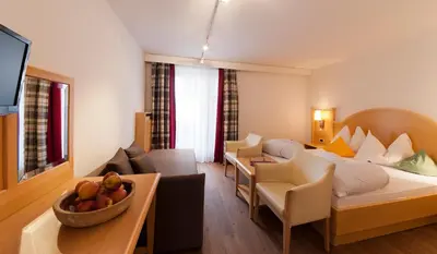 a hotel room with a bed and a couch at Geniesserhotel Messnerwirt Olang in Valdaora