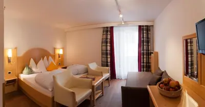 a hotel room with a bed and a living room at Geniesserhotel Messnerwirt Olang in Valdaora