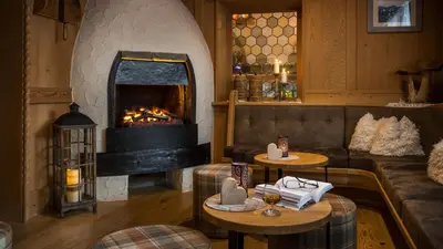 a living room with a fireplace and a couch and tables at Geniesserhotel Messnerwirt Olang in Valdaora