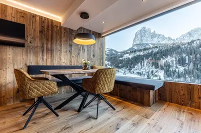 a dining room with a table and chairs and a large window at Enjoy Dolomites - Chalet in Santa Cristina in Val Gardena