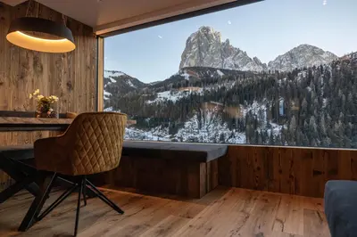 a room with a table and a chair and a large window at Enjoy Dolomites - Chalet in Santa Cristina in Val Gardena