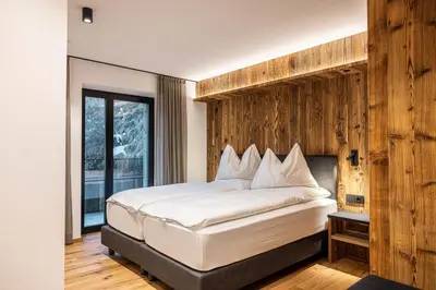 a bedroom with a large bed with a wooden wall at Enjoy Dolomites - Chalet in Santa Cristina in Val Gardena