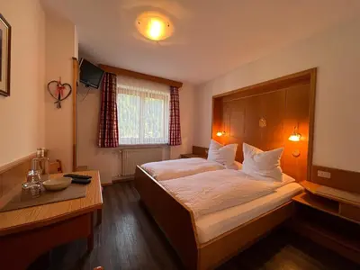 a bedroom with a large bed and a table at Enjoy Dolomites - Chalet in Santa Cristina in Val Gardena