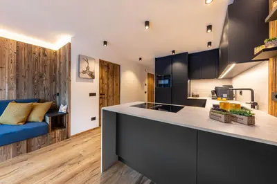 a kitchen and living room with a blue couch at Enjoy Dolomites - Chalet in Santa Cristina in Val Gardena