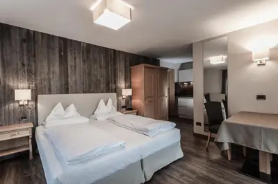 a bedroom with a large white bed and a desk at Hotel Garni Villa Park in Ortisei