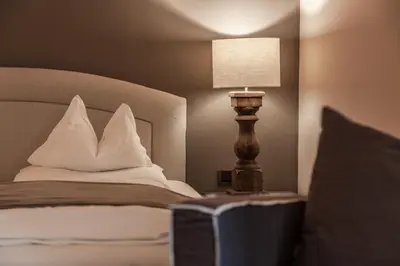 a bedroom with a bed with pillows and a lamp at Hotel Garni Villa Park in Ortisei