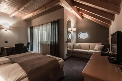 a hotel room with a bed and a couch at Hotel Garni Villa Park in Ortisei