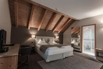 a bedroom with a bed and a desk and a mirror at Hotel Garni Villa Park in Ortisei