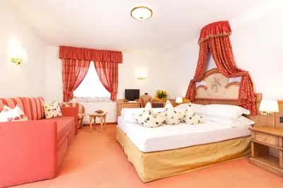 a hotel room with a bed and a couch at Nature Wellness Hotel Renato in Vigo di Fassa