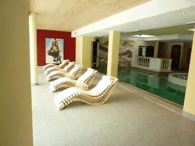 a row of white chairs sitting next to a pool at Nature Wellness Hotel Renato in Vigo di Fassa