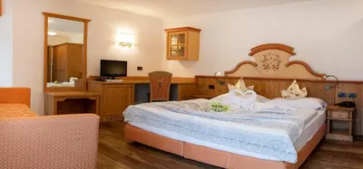 a bedroom with a large bed and a desk at Nature Wellness Hotel Renato in Vigo di Fassa