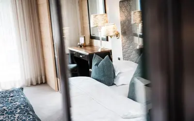 a bedroom with a bed and a desk and a mirror at Hotel Portillo Dolomites 1966' in Selva di Val Gardena