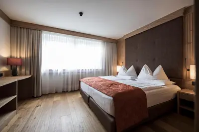a hotel room with a bed and a window at Adler Spa Resort Dolomiti in Ortisei
