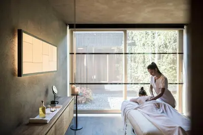 a woman sitting on a bed in a room at Adler Spa Resort Dolomiti in Ortisei
