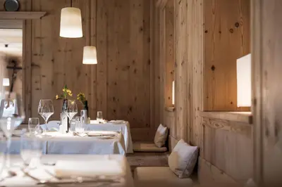 a dining room with two tables with white tablecloths at Adler Spa Resort Dolomiti in Ortisei
