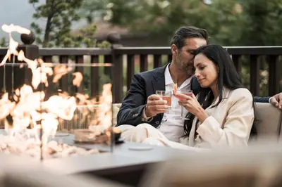 a man and a woman sitting at a table with a drink at Adler Spa Resort Dolomiti in Ortisei