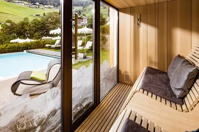 a room with a balcony with a view of a swimming pool at Grand Hotel Wolkenstein in Selva di Val Gardena