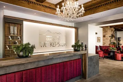 a restaurant with a red counter and a chandelier at Grand Hotel Wolkenstein in Selva di Val Gardena
