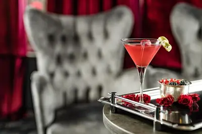 a martini glass sitting on top of a table with roses at Grand Hotel Wolkenstein in Selva di Val Gardena