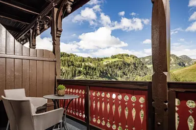a balcony with a table and chairs and a view of mountains at Grand Hotel Wolkenstein in Selva di Val Gardena