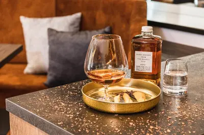 a glass of wine sitting on a table next to a bottle of whiskey at Boutique Hotel Planlim in Ortisei