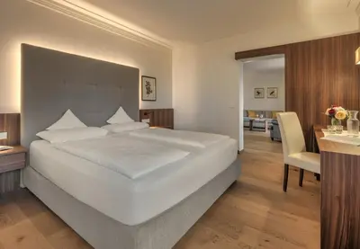 a bedroom with a large white bed and a desk at Hotel Girlanerhof in Appiano sulla Strada del Vino