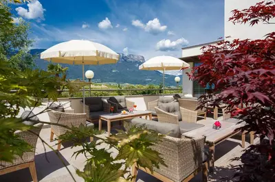 a patio with chairs and tables and umbrellas at Hotel Girlanerhof in Appiano sulla Strada del Vino