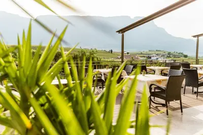 a restaurant with tables and chairs on a balcony at Hotel Girlanerhof in Appiano sulla Strada del Vino