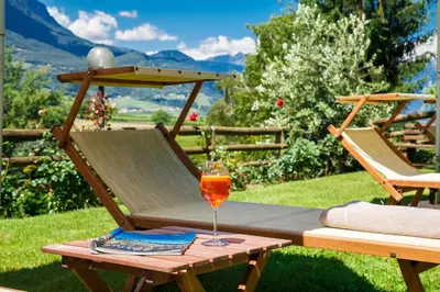 a glass of wine sitting on a table on a patio at Hotel Girlanerhof in Appiano sulla Strada del Vino