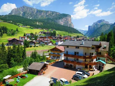a small village in the mountains with cars parked at Hotel La Pineta in Selva di Val Gardena