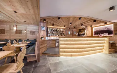 a restaurant with wooden walls and tables and a bar at Hotel La Pineta in Selva di Val Gardena